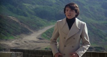 Movie still from “Harold and Maude” (1971), directed by Hal Ashby – A young man in a white coat standing on a hill; Medium shot, Low angle