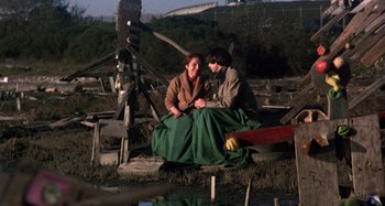 Movie still from “Harold and Maude” (1971), directed by Hal Ashby – Two people sitting next to a body of water; Wide shot, High angle