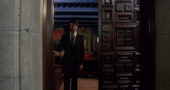 Movie still from “Harold and Maude” (1971), directed by Hal Ashby – A man in a suit standing in front of an open door; Wide shot, Low angle