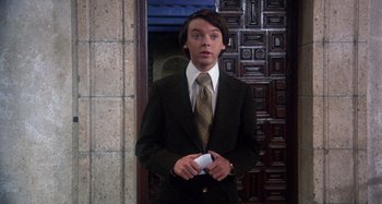 Movie still from “Harold and Maude” (1971), directed by Hal Ashby – A man in a suit and tie holding a cell phone; Medium shot, Low angle