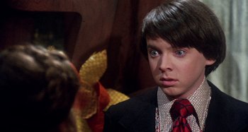 Movie still from “Harold and Maude” (1971), directed by Hal Ashby – A young man wearing a suit and tie looking into the camera; Close Up shot, Over the shoulder angle