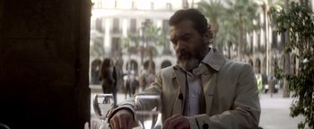 Movie still from “Haywire” (2011), directed by Steven Soderbergh – A man sitting at a table with a glass of wine; Medium shot, Low angle