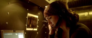 Movie still from “Haywire” (2011), directed by Steven Soderbergh – A woman wearing a headset in front of a microphone; Close Up shot, Low angle