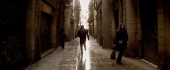 Movie still from “Haywire” (2011), directed by Steven Soderbergh – A person walking down a street with a backpack; Wide shot, Low angle
