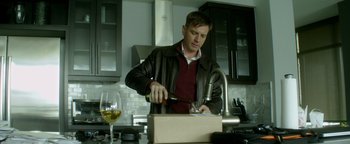 Movie still from “Haywire” (2011), directed by Steven Soderbergh – A man pouring wine into a box in a kitchen; Medium shot, Low angle