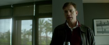 Movie still from “Haywire” (2011), directed by Steven Soderbergh – A man standing in front of a window with palm trees in the background; Medium shot, Over the shoulder angle