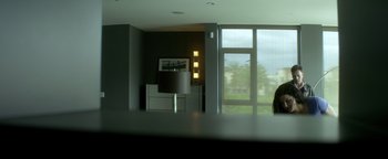 Movie still from “Haywire” (2011), directed by Steven Soderbergh – A view of a living room through a glass window; Wide shot, Low angle