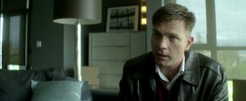 Movie still from “Haywire” (2011), directed by Steven Soderbergh – A man wearing a suit and tie sitting in front of a lamp; Close Up shot, Over the shoulder angle
