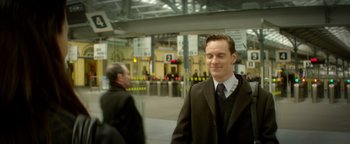 Movie still from “Haywire” (2011), directed by Steven Soderbergh – A man in a suit and tie standing in a train station; Medium shot, Low angle