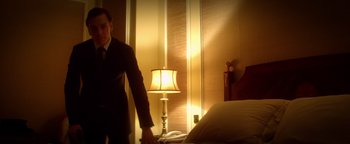 Movie still from “Haywire” (2011), directed by Steven Soderbergh – A man standing in a hotel room next to a bed; Medium shot, Low angle