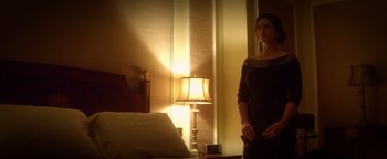 Movie still from “Haywire” (2011), directed by Steven Soderbergh – A woman standing next to a bed in a room; Medium shot, Low angle