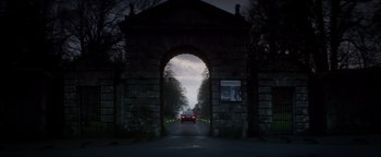 Movie still from “Haywire” (2011), directed by Steven Soderbergh – A car driving through an archway on a road; Extreme Wide shot, Low angle