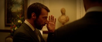 Movie still from “Haywire” (2011), directed by Steven Soderbergh – A man in a suit is holding his hand up to his face; Close Up shot, Over the shoulder angle