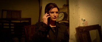 Movie still from “Haywire” (2011), directed by Steven Soderbergh – A woman is talking on a cell phone while standing in front of a clock; Close Up shot, Low angle