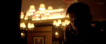 Movie still from “Haywire” (2011), directed by Steven Soderbergh – A man talking on a cell phone in front of lights; Close Up shot, Low angle