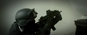 Movie still from “Haywire” (2011), directed by Steven Soderbergh – A man in a black uniform holding a rifle; Extreme Close Up shot, Low angle