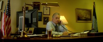 Movie still from “Haywire” (2011), directed by Steven Soderbergh – A man sitting at a desk talking on the phone; Medium shot, Low angle