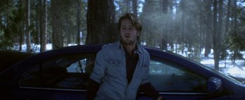 Movie still from “Haywire” (2011), directed by Steven Soderbergh – A man leaning on the hood of a blue car; Medium shot, Low angle
