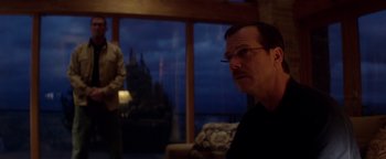 Movie still from “Haywire” (2011), directed by Steven Soderbergh – A man with glasses is sitting in front of a window; Medium shot, Over the shoulder angle