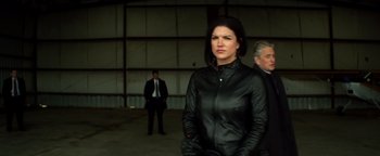 A woman in a leather jacket standing in front of two other men
