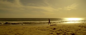Movie still from “Haywire” (2011), directed by Steven Soderbergh – A man walking on the beach near the ocean; Extreme Wide shot, Low angle