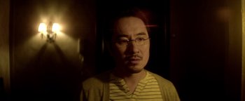 Movie still from “Haywire” (2011), directed by Steven Soderbergh – A person wearing glasses and a striped shirt; Close Up shot, Over the shoulder angle