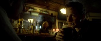 Movie still from “Haywire” (2011), directed by Steven Soderbergh – A man holding a glass of beer at a bar; Close Up shot, Low angle