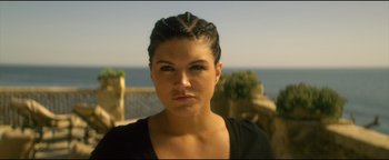 Movie still from “Haywire” (2011), directed by Steven Soderbergh – A person wearing a black shirt near a body of water; Close Up shot, Low angle