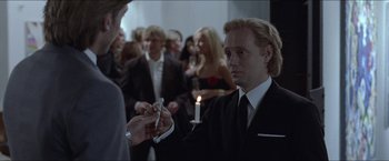 Movie still from “Headhunters” (2011), directed by Morten Tyldum – A man in a black suit is holding a cigarette; Close Up shot, Over the shoulder angle