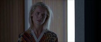 Movie still from “Headhunters” (2011), directed by Morten Tyldum – A woman with long blonde hair standing in front of a window; Close Up shot, Over the shoulder angle