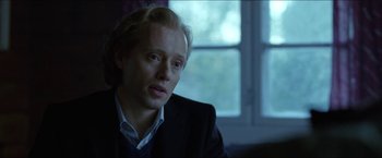 Movie still from “Headhunters” (2011), directed by Morten Tyldum – A man with blonde hair sitting in front of a window; Close Up shot, Over the shoulder angle