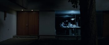Movie still from “Headhunters” (2011), directed by Morten Tyldum – A group of people sitting at a table in a dark room; Wide shot, Over the shoulder angle