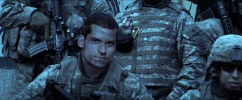 Movie still from “Headhunters” (2011), directed by Morten Tyldum – A man in a military uniform sitting next to another man in camouflage; Close Up shot, Low angle