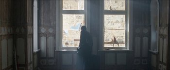 Movie still from “Headhunters” (2011), directed by Morten Tyldum – A person sitting in a room looking out of a window; Wide shot, Low angle