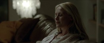 Movie still from “Headhunters” (2011), directed by Morten Tyldum – A woman sitting on top of a couch with her eyes closed; Close Up shot, Over the shoulder angle