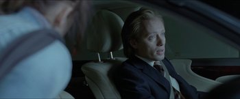 Movie still from “Headhunters” (2011), directed by Morten Tyldum – A man sitting in the back seat of a car; Close Up shot, Over the shoulder angle