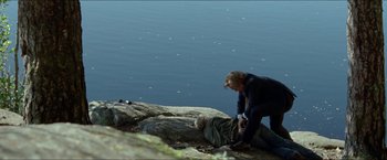Movie still from “Headhunters” (2011), directed by Morten Tyldum – Two people on a cliff near a body of water; Wide shot, High angle