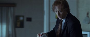Movie still from “Headhunters” (2011), directed by Morten Tyldum – A man in a suit and tie holding a box of playing cards; Close Up shot, Over the shoulder angle