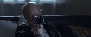 Movie still from “Headhunters” (2011), directed by Morten Tyldum – An older man holding a gun in a dark room; Close Up shot, Low angle