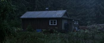 Movie still from “Headhunters” (2011), directed by Morten Tyldum – A man standing in front of a house in the rain; Extreme Wide shot, Over the shoulder angle