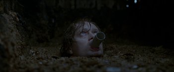 Movie still from “Headhunters” (2011), directed by Morten Tyldum – A man laying in the dirt with a tube in his mouth; Close Up shot, Low angle