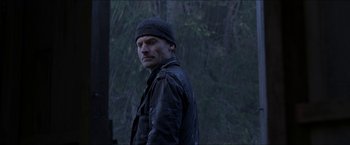Movie still from “Headhunters” (2011), directed by Morten Tyldum – A man standing in the rain wearing a hat; Close Up shot, Low angle