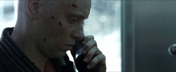 Movie still from “Headhunters” (2011), directed by Morten Tyldum – A man with blood all over his face is talking on the phone; Close Up shot, Low angle