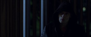 Movie still from “Headhunters” (2011), directed by Morten Tyldum – A man wearing a black hooded jacket sitting in front of a window; Close Up shot, Low angle