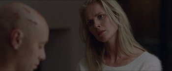 Movie still from “Headhunters” (2011), directed by Morten Tyldum – A woman with long blonde hair is looking at the camera; Close Up shot, Over the shoulder angle