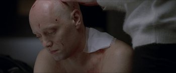 Movie still from “Headhunters” (2011), directed by Morten Tyldum – A man with bandages around his neck and chest; Close Up shot, Over the shoulder angle