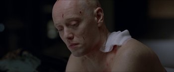 Movie still from “Headhunters” (2011), directed by Morten Tyldum – A bald man with blood on his neck and chest; Close Up shot, Overhead angle