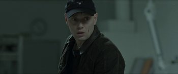 Movie still from “Headhunters” (2011), directed by Morten Tyldum – A man in a black hat and a brown jacket; Close Up shot, Over the shoulder angle