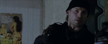 Movie still from “Headhunters” (2011), directed by Morten Tyldum – A person holding a gun in a room; Close Up shot, Low angle