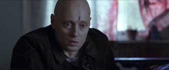 Movie still from “Headhunters” (2011), directed by Morten Tyldum – A man with a shaved head and a scar on his forehead; Close Up shot, Low angle